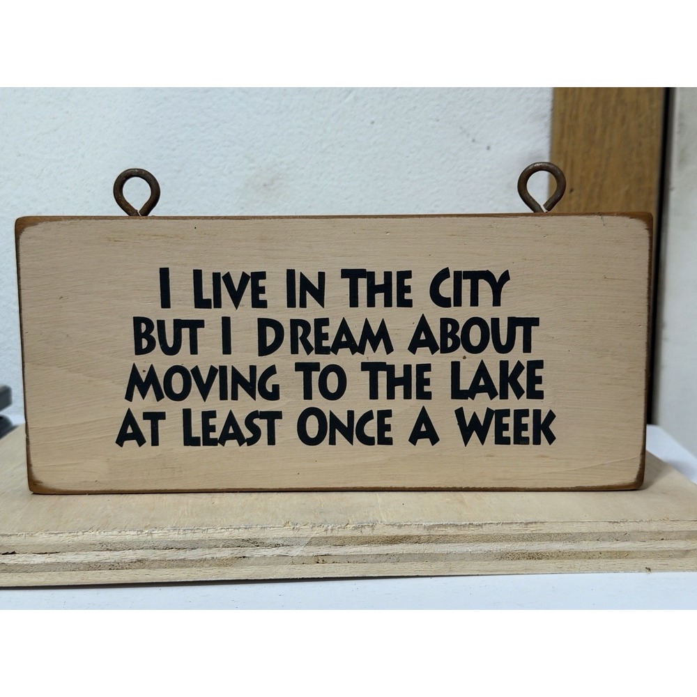 wooden sign with "I live in the city but I dream about moving to the lake